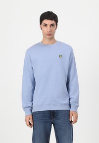 Sudadera azul claro hecha de tela suave, con mangas largas y escote redondo. Un pequeño logo amarillo está bordado en el pecho.