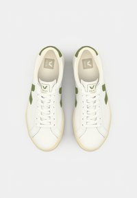 Hvite sneakers med grønne detaljer, med en glatt læroverdel, rund tå og flate lisser. Inkluderer et logo på tungen og siden.