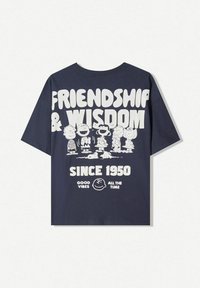 Navy short-sleeve t-shirt featuring white graphic text "FRIENDSHIP & WISDOM" and cartoon characters. "SINCE 1950" and "GOOD VIBES ALL THE TIME" included.