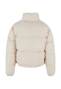 Pufferjakke i lys beige med høy krage, elastiske mansjetter og sydd horisontale paneler for en quiltet tekstur.