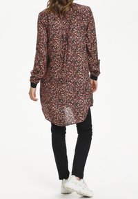Lange mouwen blouse van zwarte stof met een roze bloemenpatroon, met een ontspannen pasvorm en subtiele knoopdetails aan de achterkant.