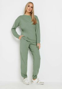 Felpa verde oliva e pantaloni da jogger abbinati realizzati in tessuto morbido, caratterizzati da una vestibilità comoda, tasche laterali e polsini a costine.