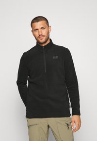 Schwarzer Fleece-Pullover mit einem Viertelreißverschluss-Kragen. Mit kleinem Logo auf der Brust und langen Ärmeln. Weiche Textur und lässige Passform.
