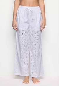 Pantaloni larghi grigio chiaro realizzati in cotone ricamato con ritagli floreali e dettagli scuri. Presentano una vita elasticizzata e un cordoncino.