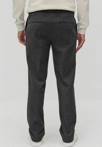 Donkergrijze broek met een getailleerde pasvorm. Beschikt over een soepele textuur, standaardzakken en subtiele details op de achterzak. Zichtbare elastische tailleband.
