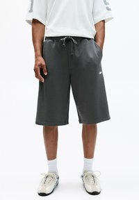 Gray cotton shorts with an elastic waistband and drawstring, featuring side pockets and a small logo on the left leg.
