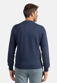 Felpa blu navy con collo rotondo a costine, maniche lunghe e polsini e orlo a costine. Tessuto liscio con una vestibilità comoda.