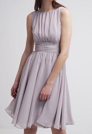 Bez rękawów, jasnofioletowa sukienka o długości do kolan z marszczonym pasem i plisowanym bodicem, noszona przez kobietę na jednolitym tle.