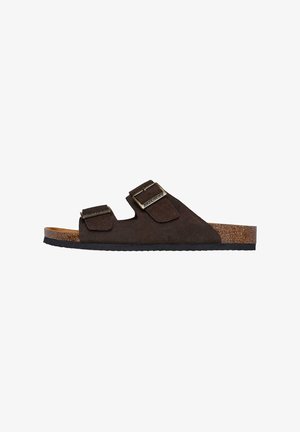 Sandali in suede marrone con due fibbie regolabili, plantare in sughero e suola in gomma. Presentano un design neutro e una texture morbida.