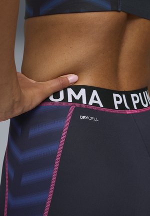 Sort elastisk talje med "PUMA" logo, stof i mørkegrå med blåt chevronmønster, pink syning detalje, mærket "DRYCELL."