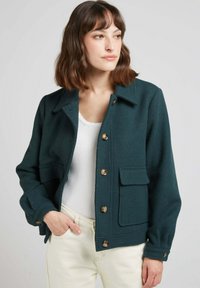 Veste boutonnée vert foncé en mélange de laine, avec un col évasé, deux poches avant et des boutons dorés, ayant une texture douce.