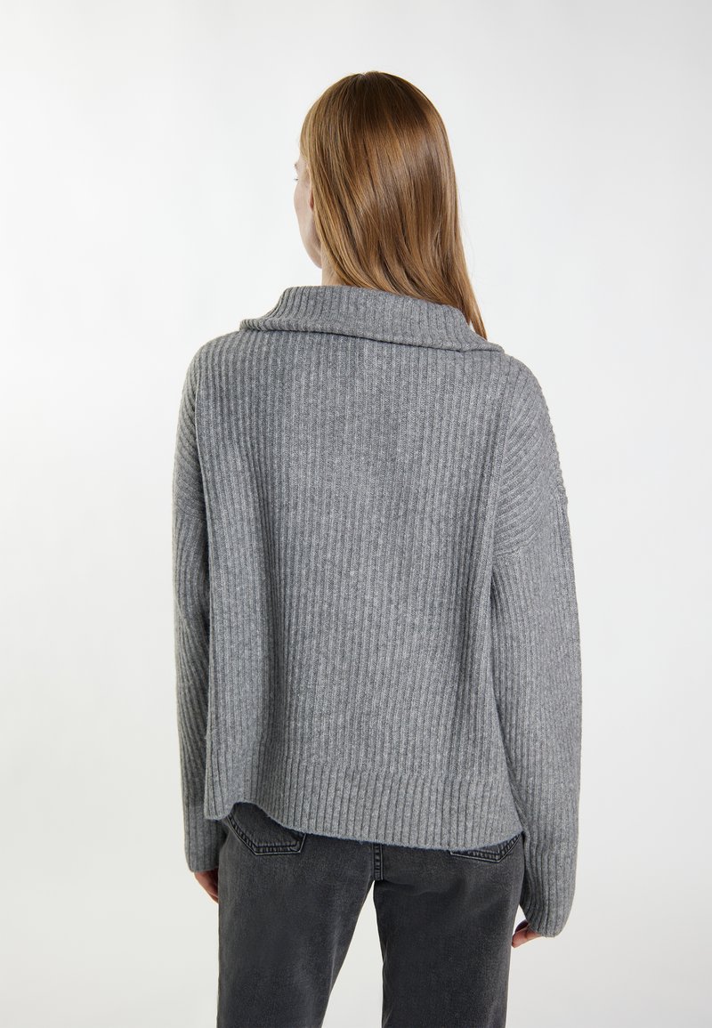 Grauer gerippter Pullover mit weitem Kragen, der eine lockere Passform und überschnittene Schultern aufweist. Texturiertes Strickmuster und Rippungen durchgehend.