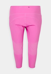 Rózsaszín capri leggings sima, rugalmas anyagból. Széles derékpánttal rendelkezik, és finom átmeneti mintázat jellemzi a telített rózsaszínből a világosabb rózsaszínbe.
