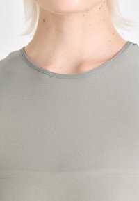 T-shirt gris clair avec une texture lisse, un col rond et des manches courtes. Design simple, sans motifs ni embellissements visibles.