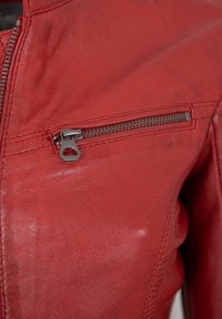 Rote Lederjacke mit einer Reißverschlusstasche auf der Brust, die über eine glatte Textur und eine dezente Maserung verfügt und das schlanke Design betont.