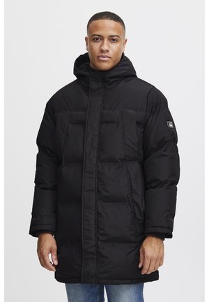 Chaqueta acolchada negra con capucha, que presenta un cierre de cremallera, dos grandes bolsillos frontales y una tela texturizada. Diseño robusto y aislante.