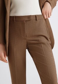 Pantaloni a quadri marroni realizzati in tessuto testurizzato, con un design aderente, gamba dritta e passanti per cintura.