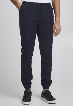 Navy blue jogger pants made of lightweight fabric, featuring an elastic waistband with drawstring and elastic cuffs at the ankles.