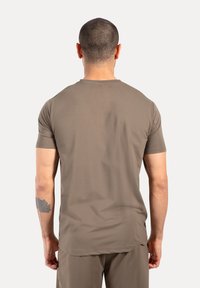 Koszulka z krótkim rękawem, okrągłym dekoltem w jasnobrązowym kolorze; wykonana z gładkiego, lekkiego materiału. Posiada prosty design bez widocznych logo.