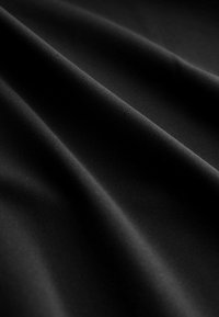 Čierna látka s hladkou textúrou a jemnými vlnkami. Materiál je pružný, jemne tkaný a s matným povrchom.