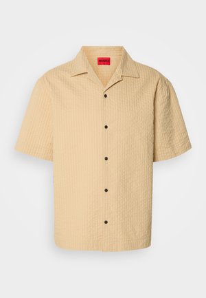 Short-sleeve, collared shirt in light beige textured fabric with a checkered pattern and black buttons. Label visible inside neckline.