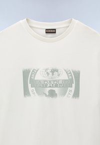Lys beige t-skjorte med korte ermer som har et falmet grønt grafisk design av en globe og landskap. Rund hals med ribbestrikket kant. Myk stofftekstur.