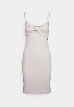 Helles beigefarbenes Bodycon-Kleid mit dünnen Trägern, das über ein gedrehtes Frontdetail und ein dezentes Calvin Klein-Logo am Hüftbereich verfügt. Sanfte Textur.