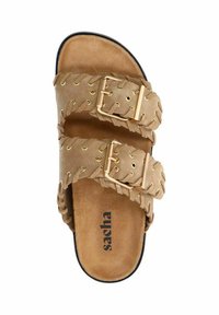 Beige suède slipper met twee gevlochten banden, voorzien van gouden gespen en ogen, platte zool en een gegraveerd logo op de binnenzool.