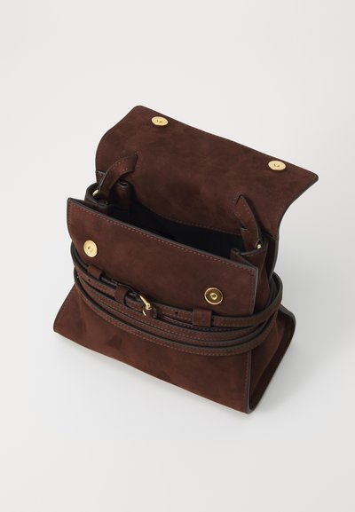 Geantă din suede maro cu accente aurii, un design deschis în partea de sus și un breloc detașabil. Prezintă o textură netedă și detalii cusute.
