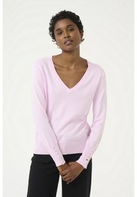 Maglione rosa a V con maniche lunghe, dotato di dettagli a bottoni sui polsini, realizzato in un materiale morbido e leggero. Pantaloni neri visibili.