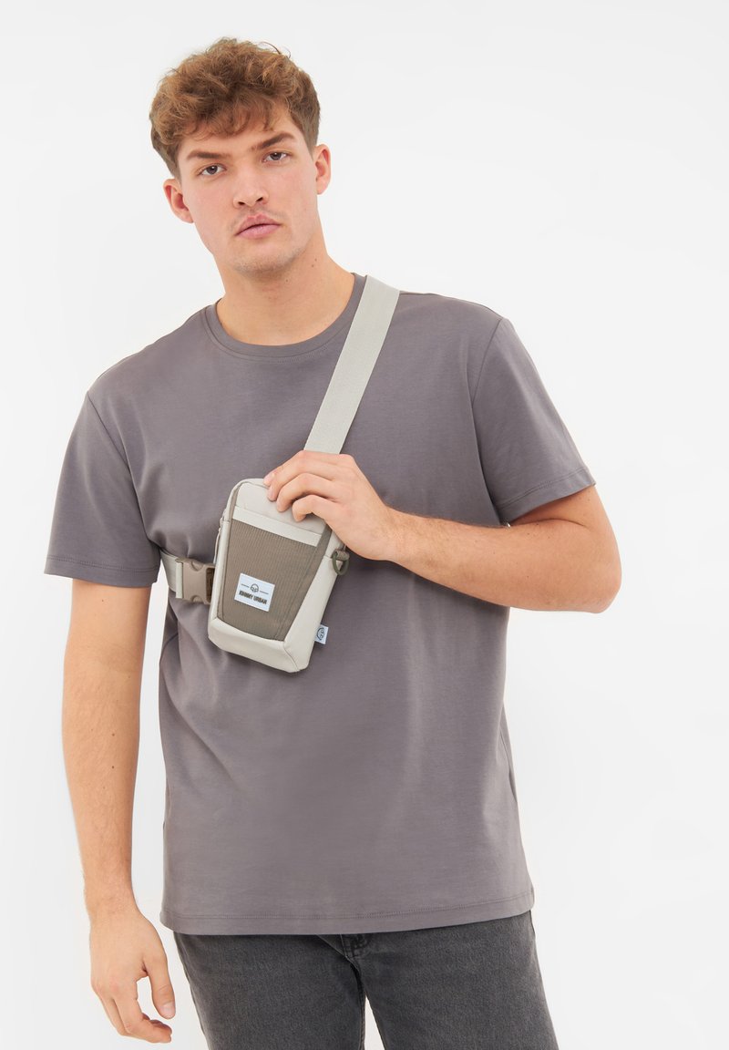 Borsa a spalla grigia con dettagli e tracolla grigia chiara, caratterizzata da un pannello frontale testurizzato e un piccolo logo. Indossata a tracolla.