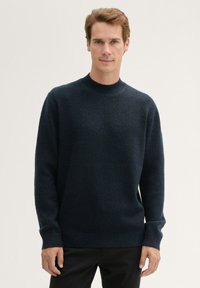 Pull en maille bleu marine foncé avec un col rond, des manches longues, des poignets et un ourlet côtelés. Texture douce avec un motif subtil et uniforme.