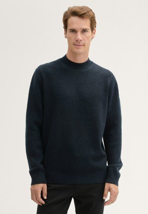 Pull en maille bleu marine foncé avec un col rond, des manches longues, des poignets et un ourlet côtelés. Texture douce avec un motif subtil et uniforme.
