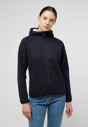 Marineblauwe zip-up hoodie van een gestructureerde stof, gevoerd met beige fleece aan de binnenkant van de capuchon. Beschikt over zijzakken met rits en een aansluitend ontwerp.