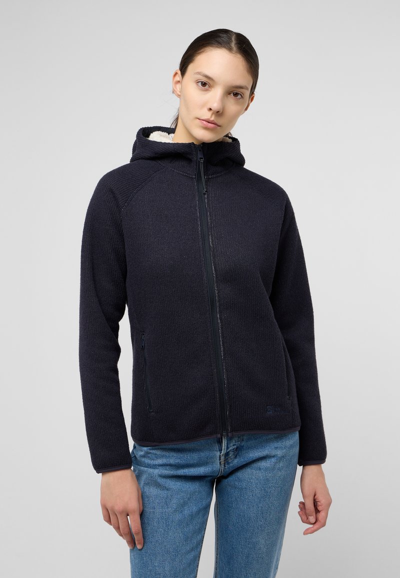 Marineblauer Zip-Hoodie aus strukturiertem Material, innen mit beigem Fleece im Kapuzenfutter ausgestattet. Verfügt über seitliche Reißverschlusstaschen und ein tailliertes Design.