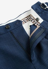 Marineblauwe trousers van gestructureerde stof, met een ritssluiting, twee knopen en een gestreepte binnenband in crème en bruin.