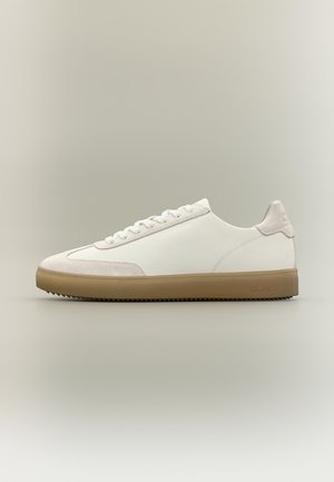 Hvid lavtop-sneakers med beige gummisål, ruskindsdetaljer ved tå og hæl samt hvide snørebånd på neutral baggrund.