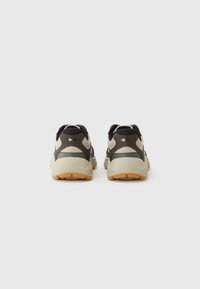 Schwarze und beige Sportschuhe mit einem Mesh-Obermaterial, Gummisohle, gepolstertem Kragen und minimalistischen Design. Texturierte Akzente verbessern die Stabilität.