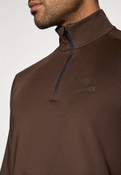 Brun halvdraget tröja med slät textur. Har en kontrasterande svart dragkedja och en diskret märkeslogotyp på det övre bröstområdet.