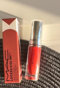 MAC Locked Kiss Ink flytande läppstift i röd, med en klar glasbehållare, silverlock och en fyrkantig orange låda med svart text.