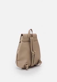 Zaino beige realizzato in materiale morbido, con un'apertura pieghevole, due spallacci regolabili e dettagli in hardware dorato.