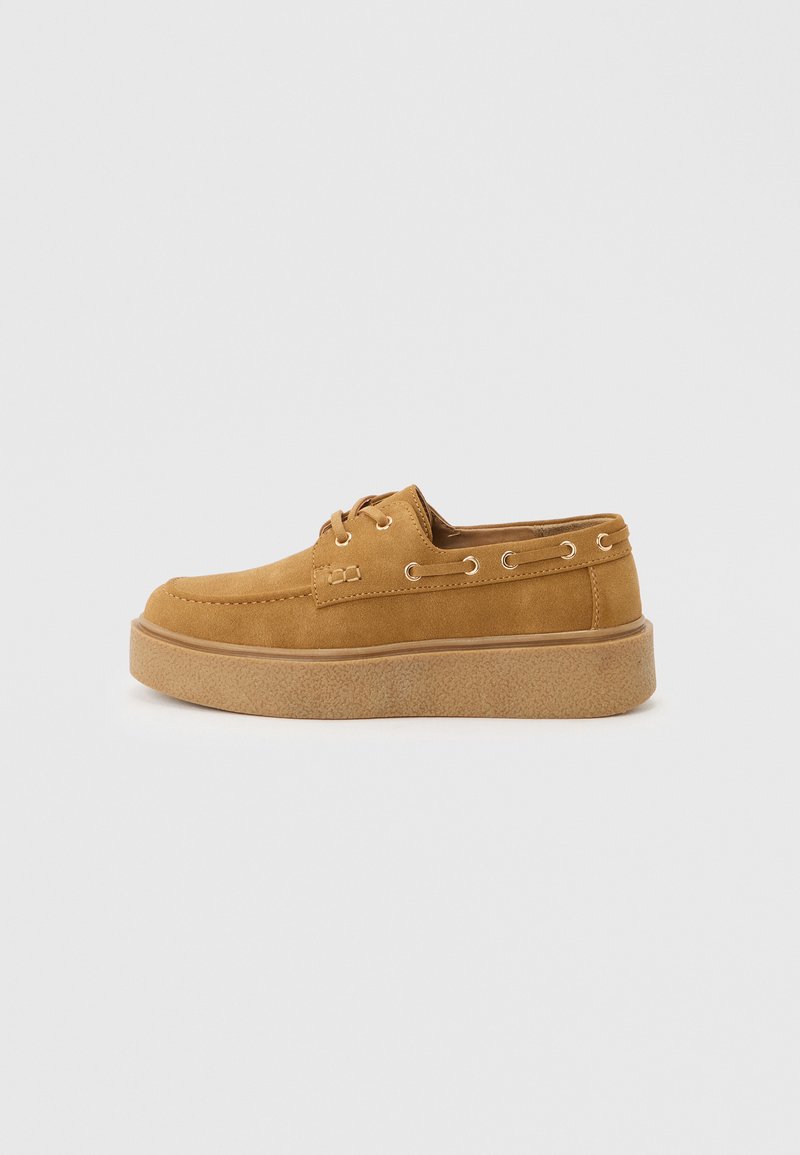 Ανοιχτό καφέ καστόρινο καθημερινό παπούτσι με κορδόνια, ραφή moc toe, μεταλλικά ρουχιστικά και παχύ υφασμάτινο πάτο σε ανοιχτό φόντο.