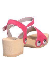 Sandale en daim rose avec talon bloc en bois, bout ouvert, clous décoratifs argentés et bride arrière réglable avec boucle.