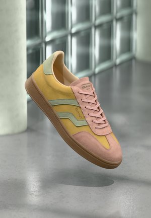 Tenisky v ružovej, žltej a zelenej semišovej úprave s textúrovanou gumovou podrážkou. Obsahujú šnúrky, branding a vrstvené dizajnové akcenty.