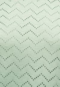 Ανοιχτό πράσινο ύφασμα με υφασμένο ζιγκ-ζαγκ μοτίβο από μικρές διάτρητες οπές σε ομοιόμορφα κατανεμημένες σειρές.