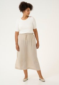 Let italiens beige linneskørt med elastisk talje og snor. Sæt sammen med en tætsiddende hvid kortærmet top og let fodtøj.