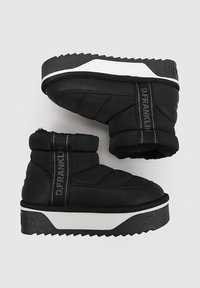 Botas de tobillo acolchadas negras con una suela de plataforma gruesa blanca. Las características incluyen un acento de logo y textura acolchada en los lados.