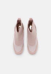 Scarpe rosa slip-on con tomaia in maglia, lati testurizzati e suola liscia a contrasto. Presentano una linguetta sul tallone per facilitarne la calzata.