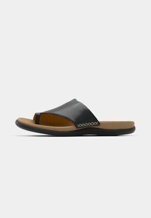Sandalia deslizante de cuero negro con puntera abierta, plantilla acolchada beige y suela de goma. Presenta costuras decorativas a lo largo del borde superior.