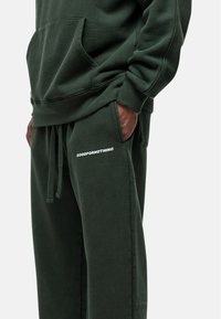 Groene katoenen hoodie met een voorvak en bijpassende sweatpants met witte "GOODFORNOTHING" tekst op de dij. Zachte textuur.